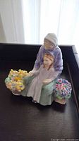 Front view of the Royal Doulton porcelain figurine showing an elderly woman with a child and flowers.