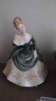Front view of Royal Doulton Soiree HN 2312 figurine showing seated woman with fan in green and cream dress.