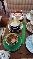 Overview of three porcelain teacup and saucer sets arranged on wooden table