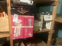 Wooden shelving with pink Barbie camper box, black Lego case, puzzle box, model car, and other items visible.