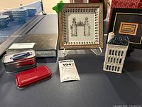 Display of the decorative plate with box, ceramic building, and other items on table.