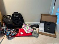 Wide view of lots showing three backpacks (two Jansport, one North Face), Jack Spade briefcase in box, and smaller bags including Zomake pouch