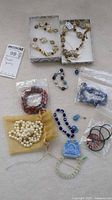 Full view of the lot showing various bracelets, necklaces, and earrings including blue evil-eye bead bracelets, pearl-like bracelets, and others in their packaging.