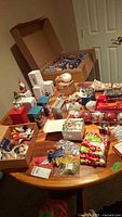 Wide view of assortment on table showing many holiday decorations and boxes with ornaments and figures.
