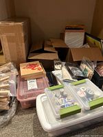 Photo of assorted craft supplies in various storage containers including plastic bins and cardboard boxes.