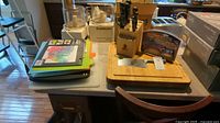 Photo shows a collection of cutting boards, a butcher block with knives, and packaged Chef's Choice Knife Sharpener on a table.