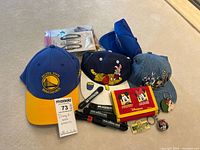 Photo showing various Disney and branded hats, wallet, hair clips, and keychains arranged on floor.
