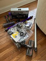 Dyson Allergy Kit box with multiple vacuum attachments and purple wand laid out