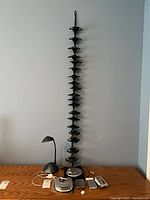 Photo showing vertical hanging black disc rack mounted on wall and items on wooden surface below including two disc players, two iPods, earphone, desk lamp, and small blue carrying case.