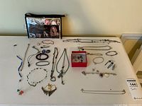 View of necklaces, bracelets, earrings, and jewelry case laid out on a flat surface