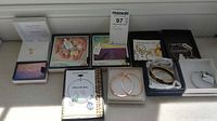 Full lot of assorted jewelry including bracelets, earrings, and necklaces arranged in boxes and display stands.