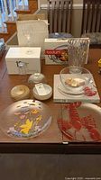 Photo shows various crystal bowls, a textured crystal vase, Bodum glass dish box, stemless flute box, unmarked champagne glasses, and decorative serving plates with lobster and butterfly designs.