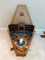Full view of the pinball style baseball game showing wooden triangular frame, backboard with stadium and scoreboard graphics, and multiple target holes.