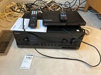 Sony AV receiver STR-DN1030 with remote and instruction manual on top, along with LG Blu-ray player BP335W and its remote, all with cables visible underneath.