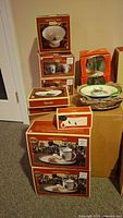 Overview photo showing multiple boxed Spode Christmas Tree items including trays, mugs, plates, and a pierced heart dish.
