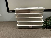 Five stacked Sterilite ClearView storage bins on carpeted floor next to wall, showing size and general condition.