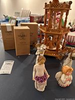 Photo showing four Willow Tree figurines including two out of box and two in boxes, and the wooden candle spinner in the background.