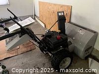 General angled view of the entire snow blower showing auger, wheels, and handle controls.