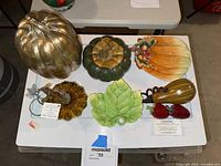 Full lot with all ceramic and glass autumn themed items displayed on a white table.