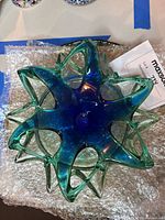 Top-down view of blue and green Murano glass star-shaped bowl showing translucent colors and organic design.