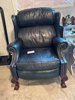 Front view of one blue leather recliner showing upholstery, brass nailhead trim and overall shape