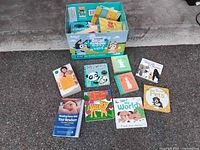 Photo showing a box filled with baby and children's books including identified titles and board books on the floor.