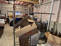 Clothing rack with cardboard boxes, wire hangers, and a white plastic laundry hamper inside, showing size and condition of rack.
