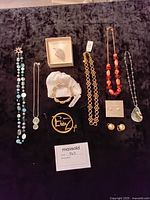 Full layout of assorted necklaces, bracelets, earrings, and brooches on dark background