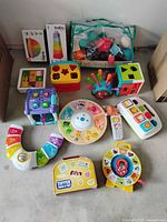 Various kids educational toys including puzzles, blocks, interactive learning devices arranged on floor