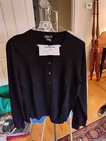 Black cashmere button-up cardigan sweater hanging on display