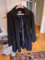 Photo of Gallery women's medium black raincoat hanging on rack, button front, collar visible