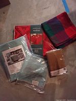 Photo of multiple linens including Lenox and Marquis by Waterford tablecloths, colorful plaid fabric, and tan napkins.