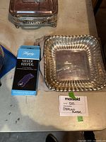 Sterling silver platter with ribbed edges shown alongside boxed silver polishing cloth and covered server in background