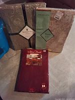 Three packaged tablecloths: Waterford Damask, Vienna tablecloth, and Autumn Harvest