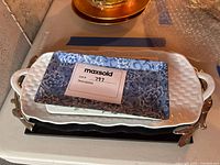 Photo showing stacked ceramic platters, including a white platter with basket weave texture and a blue floral-patterned rectangular plate with embossed details.
