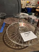 Photo showing all three glass cake stands: one clear with geometric ridges, one small pink with floral pattern, and one large pink with floral pattern.