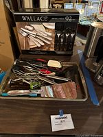 Tray with various used kitchen utensils including spatulas and peelers in multiple materials and colors.