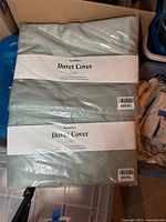 Photo of two Brooklinen Luxe duvet covers packed in their plastic wrapping showing labels.
