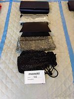 Five women's evening purses arranged on a quilted mat