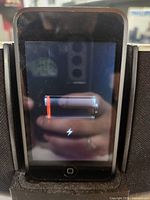 Front screen of the black Apple iPod Touch showing a low battery indicator.