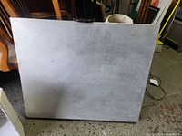 Metal folding table folded in half, showing textured top surface with some marks and scratches.