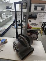 Side view of gray air mover with extended handle and coiled power cord on top.