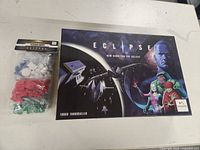 Photo of the main game box with additional unopened spaceship miniatures in plastic packaging placed beside it.