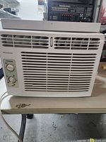 Front view of white Frigidaire window air conditioner showing air vents and control knobs for temperature and fan speed.