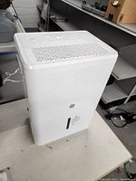 Front and side view of white G.E dehumidifier showing vented top and GE logo on front.
