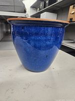 Side view of a glazed blue terracotta flower pot showing glossy blue finish and flared rim