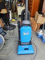 Front view of blue Hoover Tenpo upright vacuum cleaner showing body, handle, and attached hose.