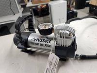 Portable Husky 120 Volt Inflator showing the pressure gauge and compact design.