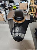 Front view of the black and silver Keurig coffee maker with top lid closed.