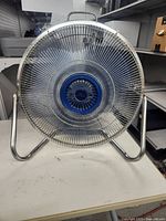Front view of the circular Lakewood fan showing its silver metal grill and blue blades with the central Lakewood logo.